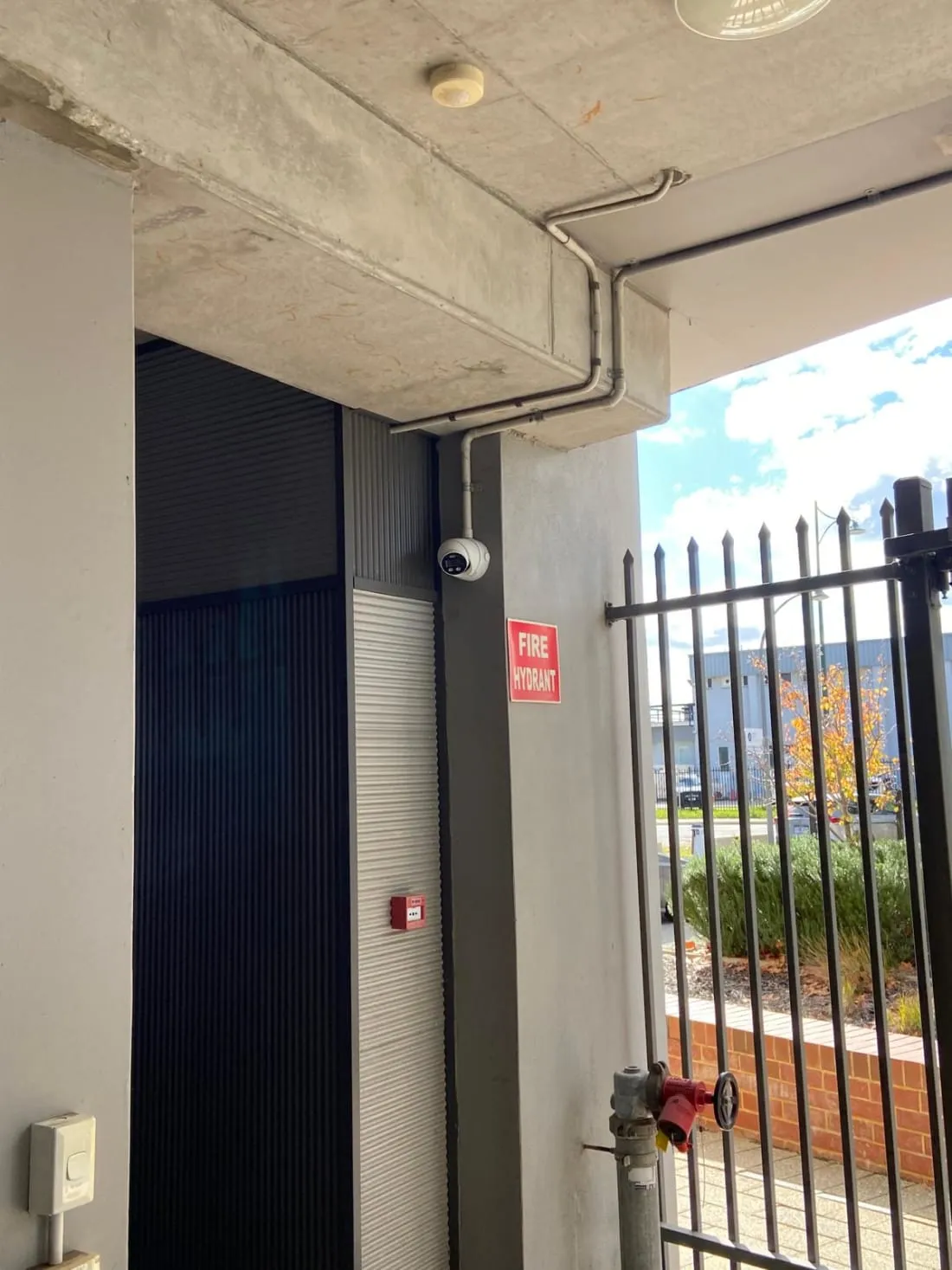 Turret camera and conduit at a commercial building entry