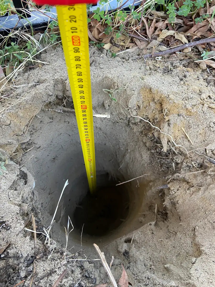 Augered footing hole for a security camera pole with a depth tape, on a Perth camera installation