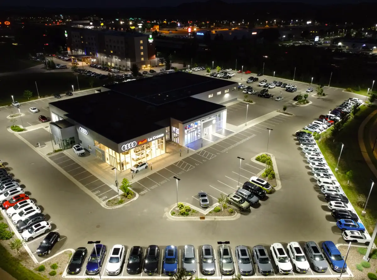 Aerial view of a car dealership and display yard with rows of vehicles at night