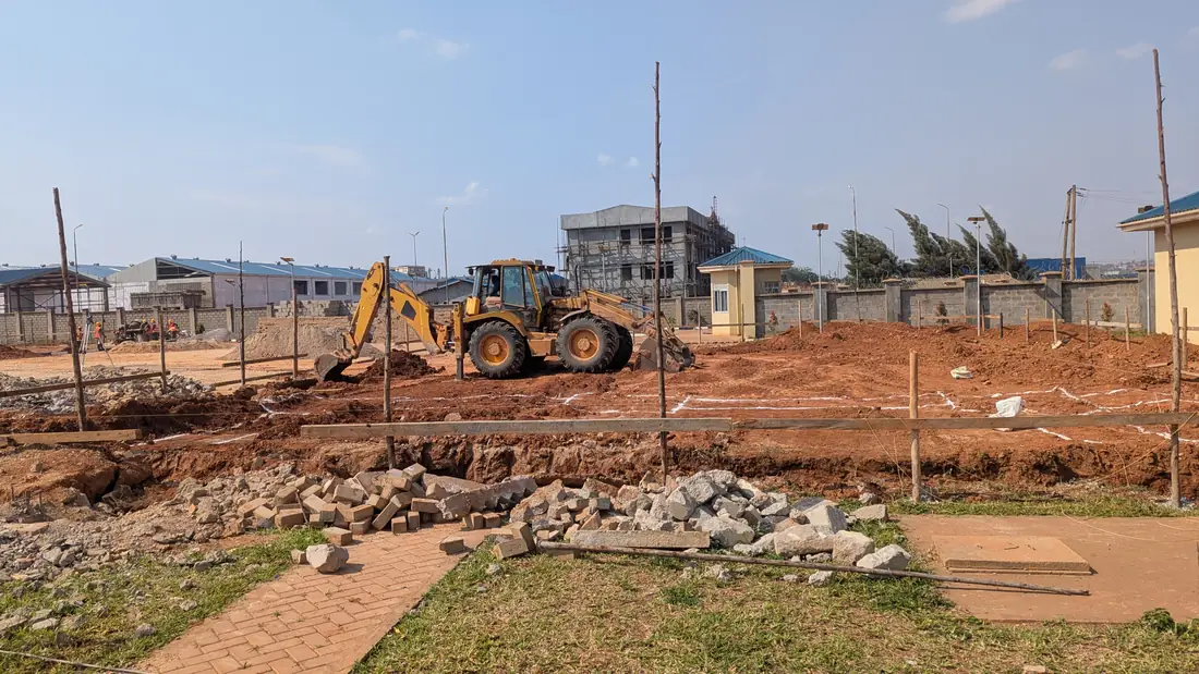 Active construction site with an excavator working beside buildings under construction